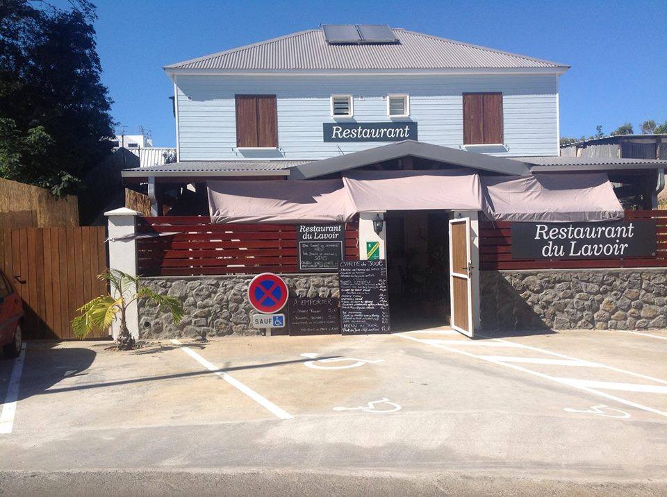 La façade du Restaurant du Lavoir à Saint-Pierre : une case créole bleu clair, sa terrasse sous auvent et les ardoises du menu du jour.