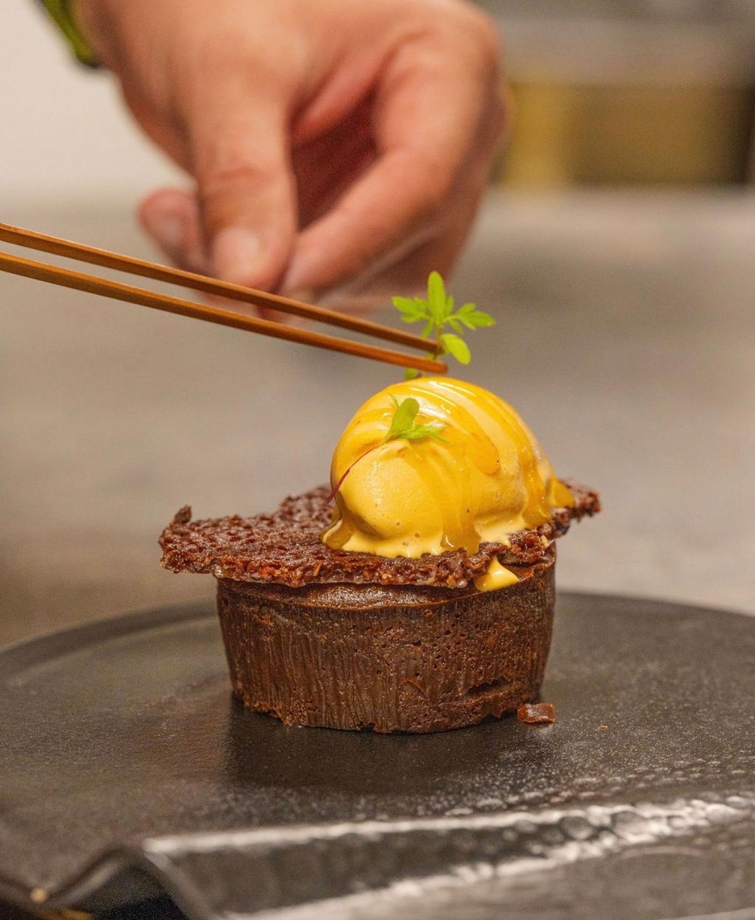 Un dessert du chef dressé à l'assiette : fondant au chocolat coiffé d'un sorbet mangue-passion.